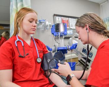 Students in Carthage's BSN in nursing program take each other's blood pressure.